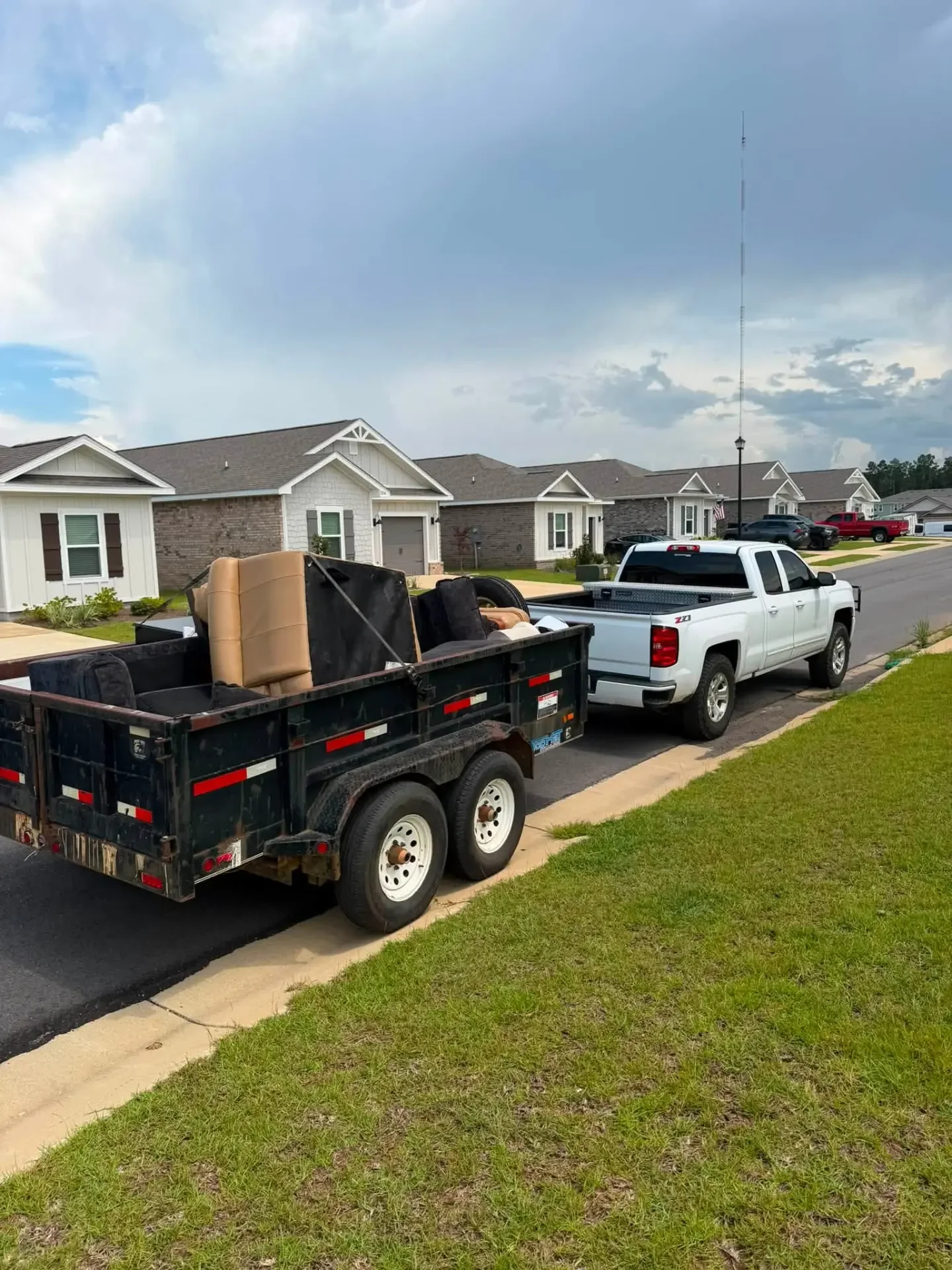 Loaded dump trailer behind a pickup truck in a Tuscaloosa neighborhood